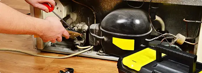 Refrigerator repair technician fixing the compressor and wiring in Buda, TX