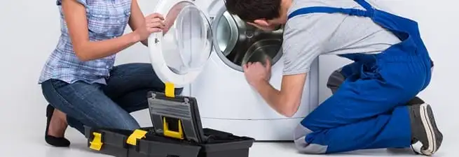 Washer repair technician inspecting a front-load washing machine with tools in Austin, TX