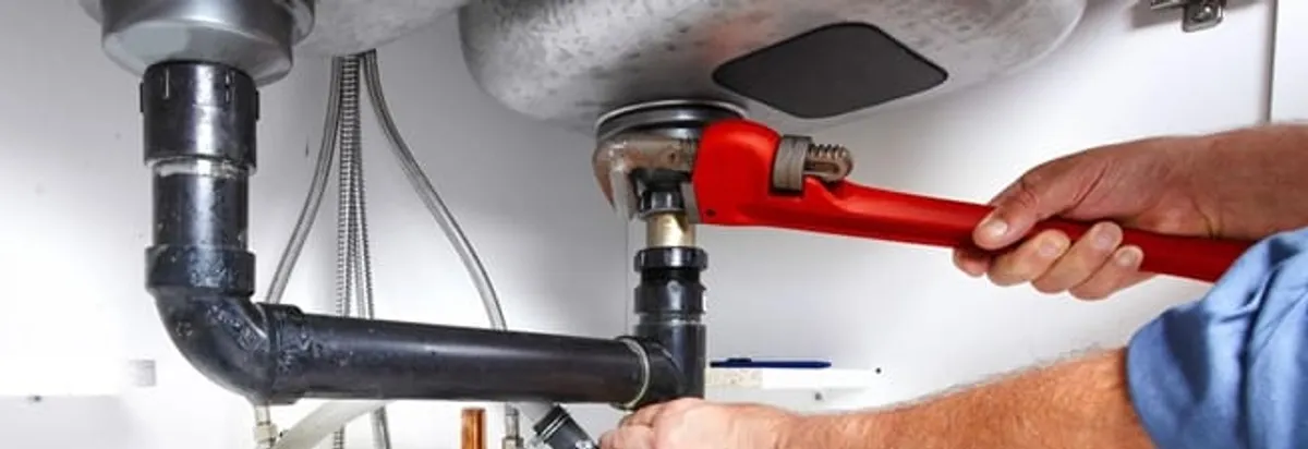 Garbage disposal repair technician tightening the sink drain and disposal connection in Austin, TX