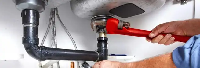 Garbage disposal repair technician tightening the sink drain and disposal connection in Austin, TX