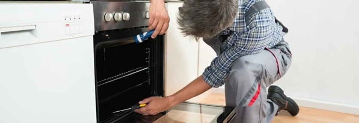 Oven repair technician inspecting and servicing an electric oven in Austin, TX