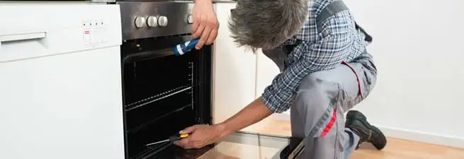 Oven repair technician inspecting and servicing an electric oven in Austin, TX