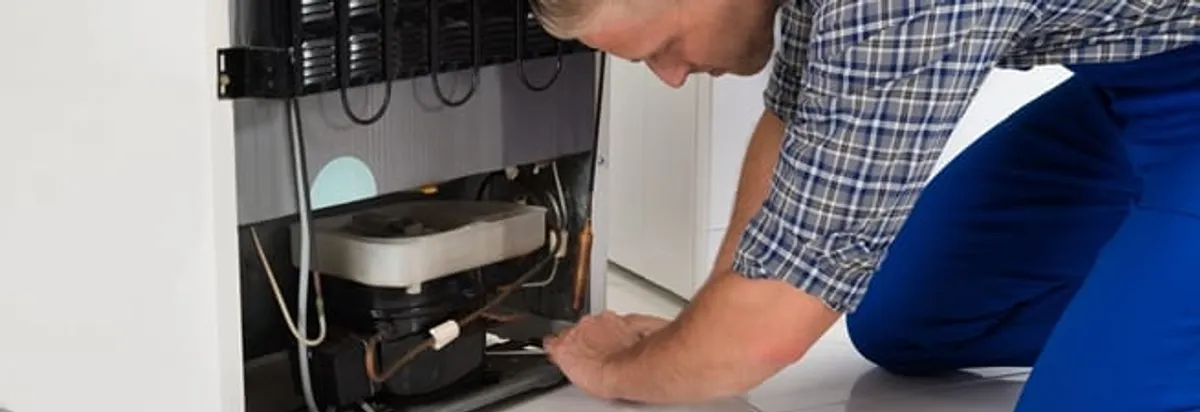 Refrigerator repair technician servicing the compressor and condenser area in Austin, TX