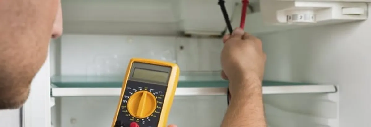 Refrigerator repair technician testing electrical components with a multimeter in Austin, TX