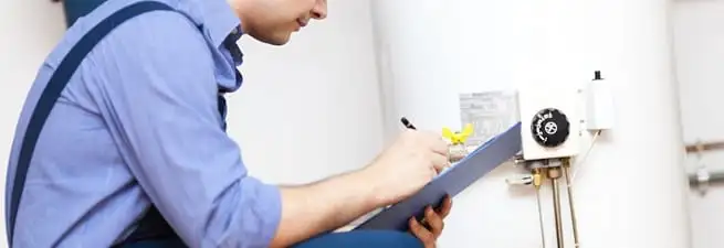 Water heater repair technician inspecting the unit and recording service notes in Austin, TX